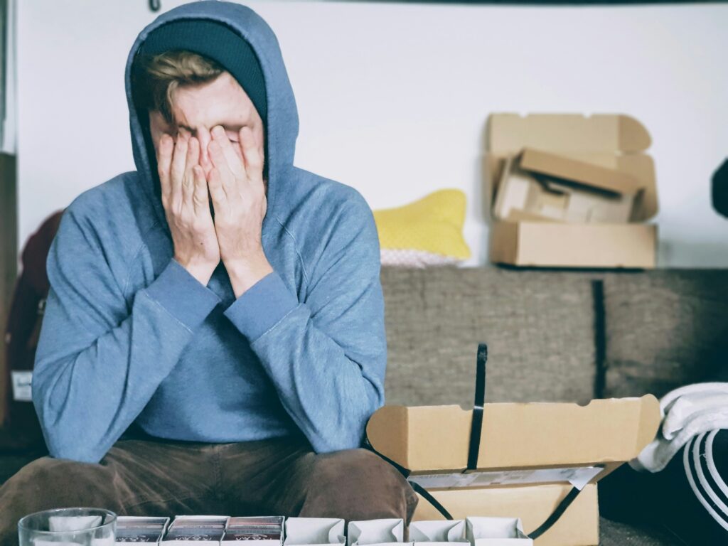 Young man struggling with sensory overload - sitting with head in hands